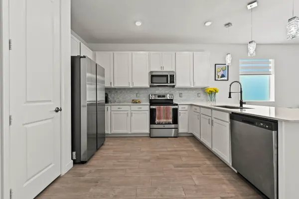 a kitchen with stainless steel appliances granite countertop a refrigerator sink and white cabinets