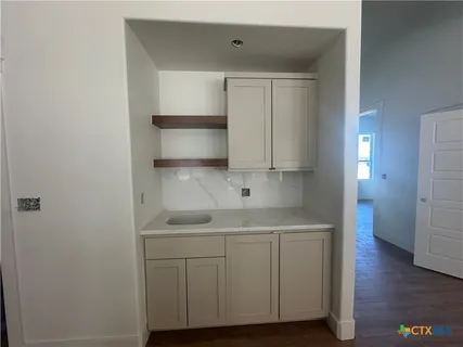 a kitchen with white cabinets and wooden floor