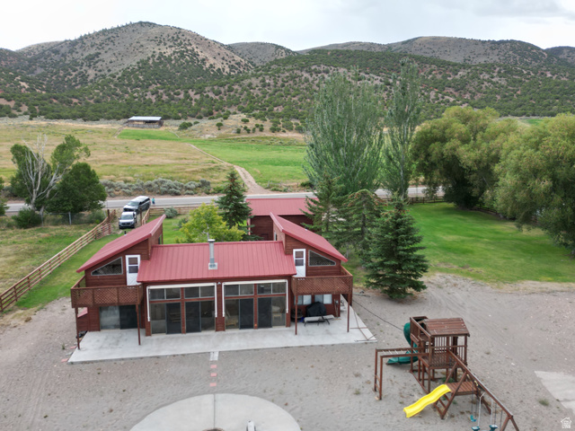 1825 North Cisco Road Laketown, UT 84038 - Photo 7 of 34 Red metal roof architecture with multiple large windows, elevated deck, and a concrete patio