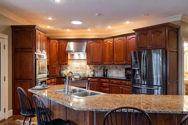 a kitchen with kitchen island granite countertop wooden cabinets a sink and appliances