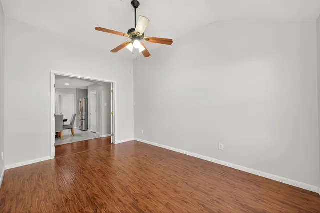 an empty room with wooden floor fan and windows