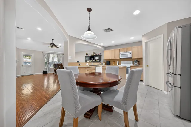 a open dining room with stainless steel appliances kitchen island granite countertop a sink a stove a dining table and chairs