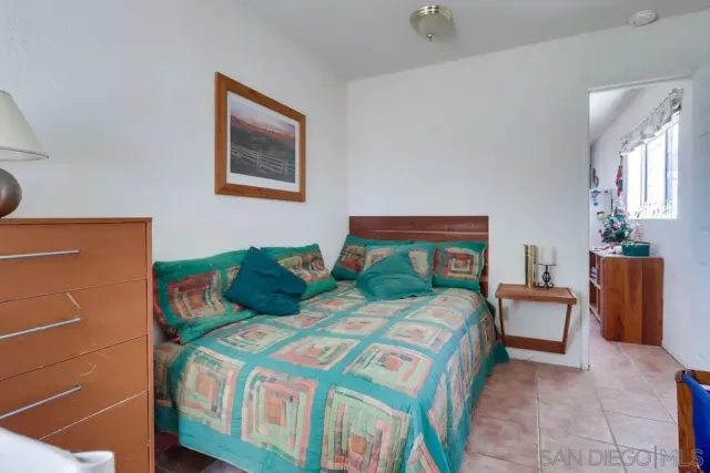 a bedroom with a bed and a lamp on dresser