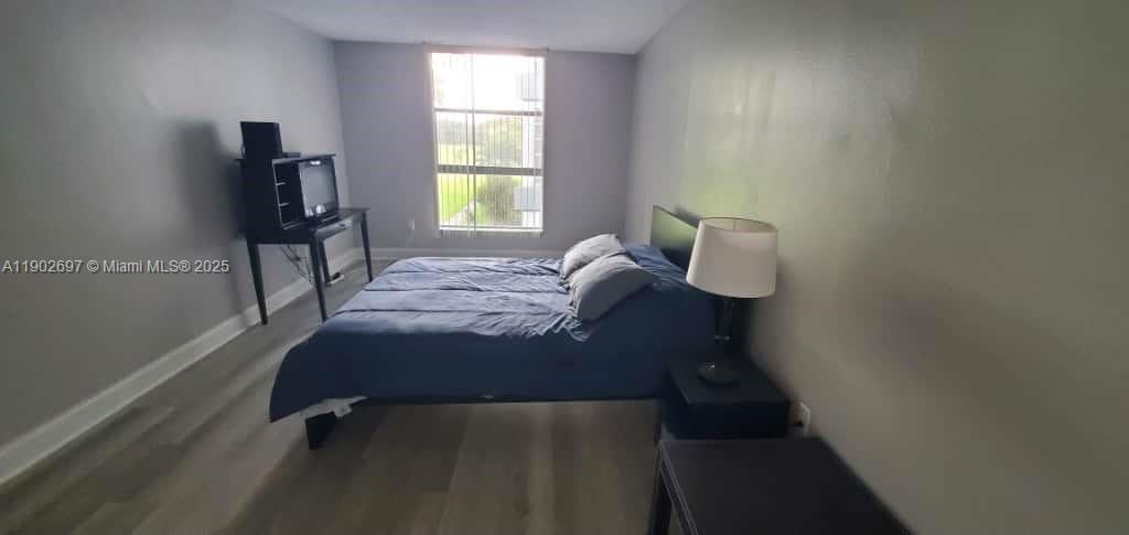 8331 Sands Point Boulevard, Unit C205 Tamarac, FL 33321 - Photo 17 of 25 a bed sitting in a bedroom next to a window