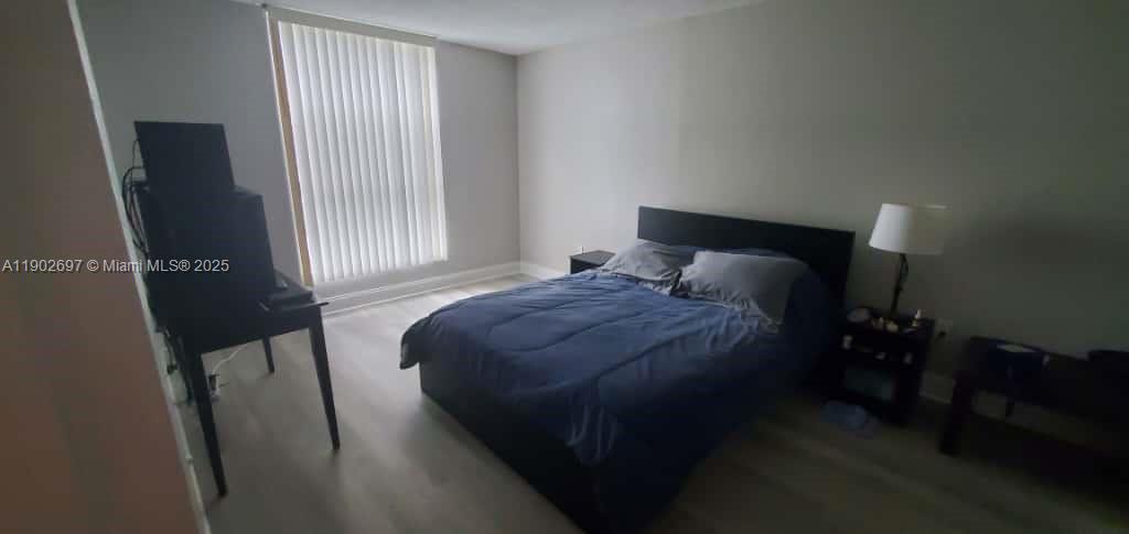 8331 Sands Point Boulevard, Unit C205 Tamarac, FL 33321 - Photo 21 of 25 a bedroom with a bed and wooden floor