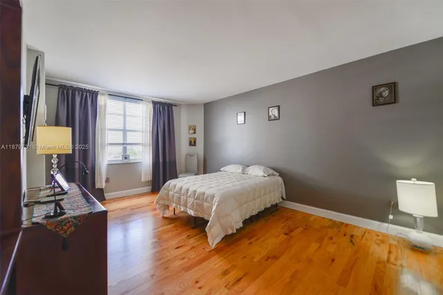 a spacious bedroom with a bed and a dresser with wooden floor