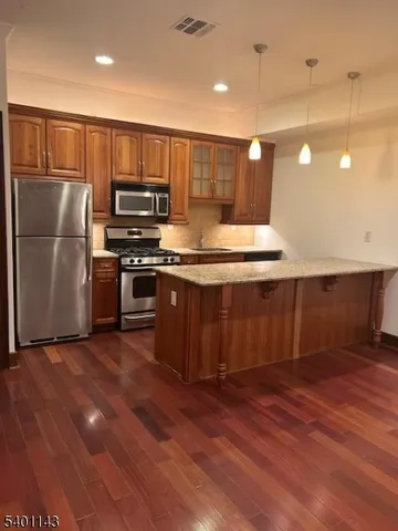 a kitchen with kitchen island a sink wooden floor and stainless steel appliances