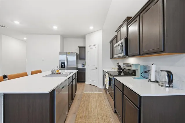 a kitchen with a sink a stove cabinets counter space and stainless steel appliances