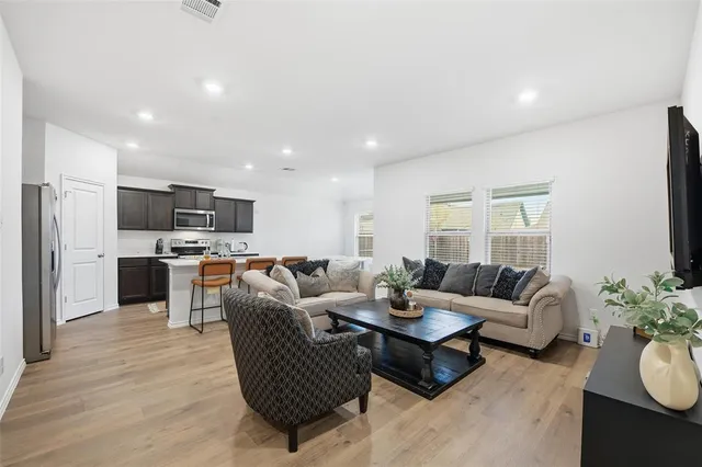 a living room with furniture kitchen area and a wooden floor