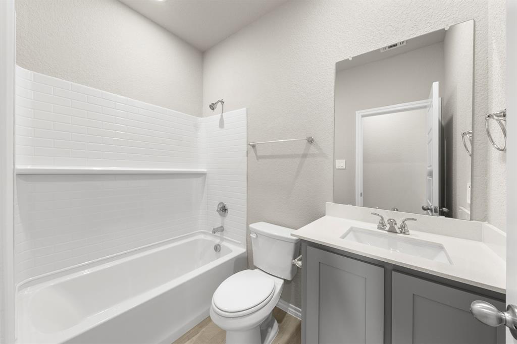 8224 Kingfisher Road Pilot Point, TX 76258 - Photo 17 of 27 a bathroom with a granite countertop toilet a sink and a bathtub