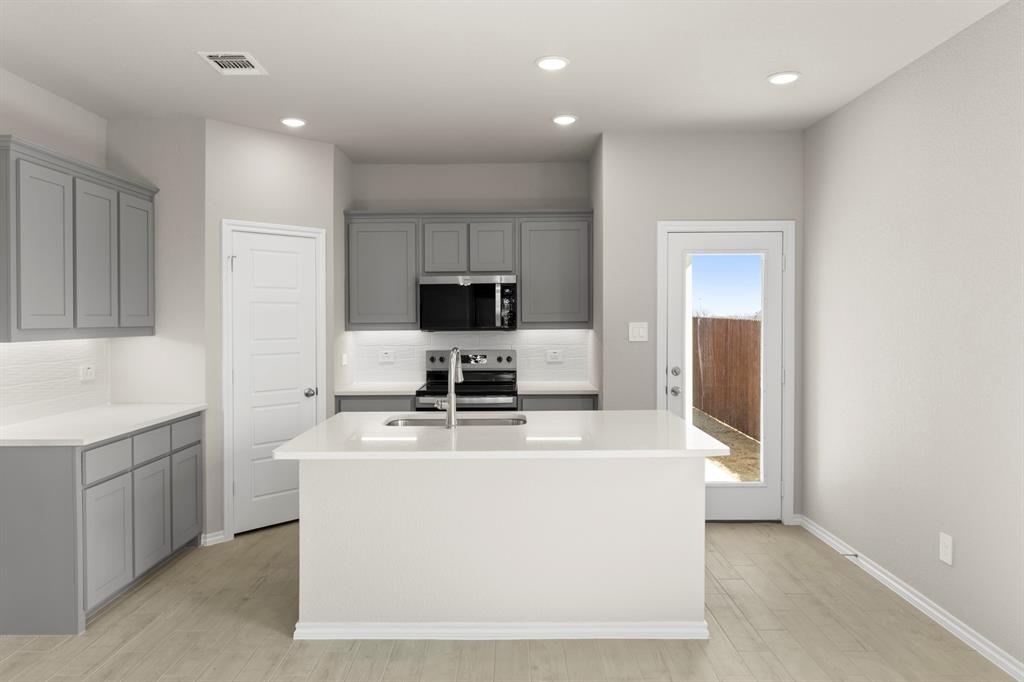 8224 Kingfisher Road Pilot Point, TX 76258 - Photo 4 of 27 a dining hall with stainless steel appliances granite countertop a sink a microwave a refrigerator and white cabinets with wooden floor