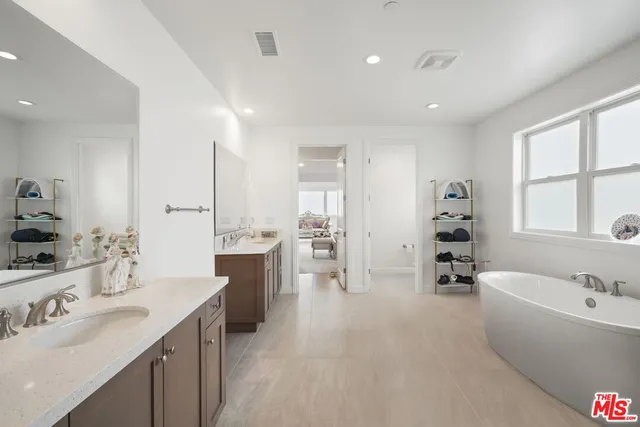 a large white bathroom with a tub a sink and a large mirror