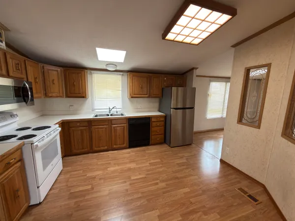 a kitchen with stainless steel appliances granite countertop a stove a sink dishwasher a refrigerator and a stove with wooden floor