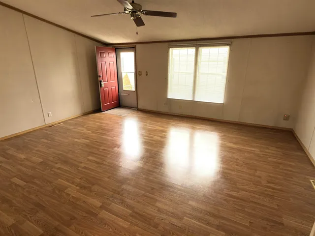 an empty room with wooden floor fan and windows