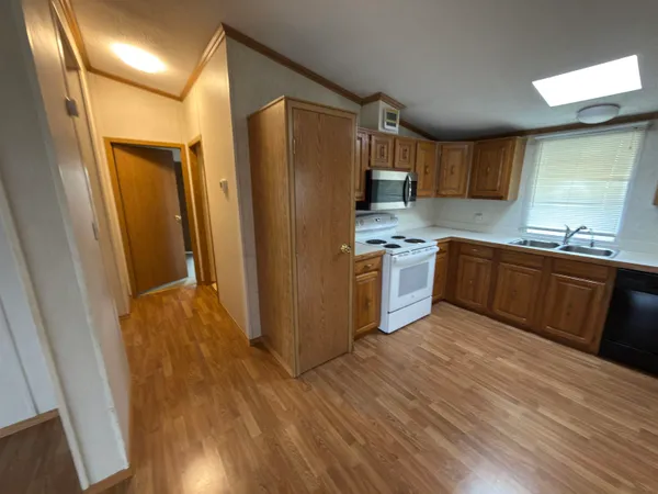 a kitchen with stainless steel appliances granite countertop a refrigerator a sink dishwasher and wooden cabinets with wooden floor