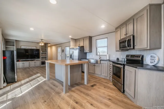 a kitchen with granite countertop a stove top oven a sink dishwasher a refrigerator and white cabinets with wooden floor