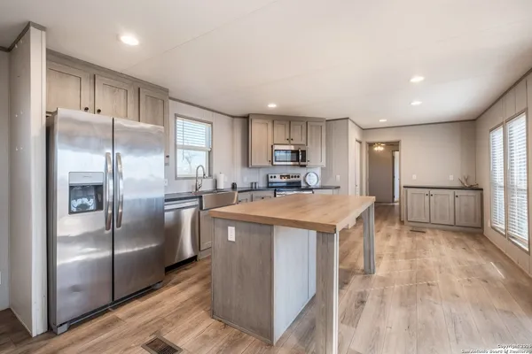 a kitchen with stainless steel appliances granite countertop a refrigerator a sink a stove and a refrigerator