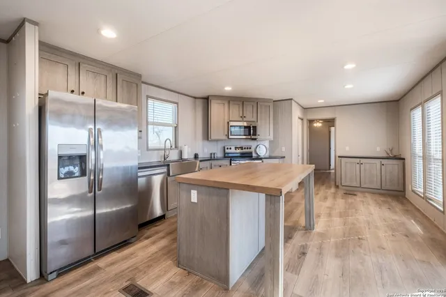 a kitchen with stainless steel appliances granite countertop a refrigerator a sink a stove and a refrigerator