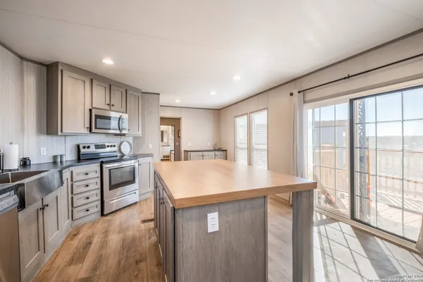 a kitchen with kitchen island granite countertop a stove top oven a sink a counter space and cabinets
