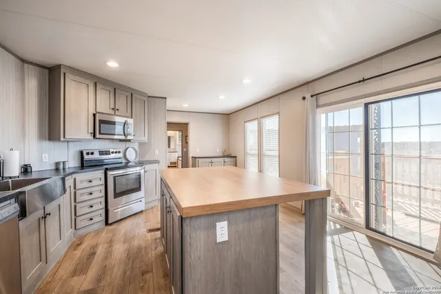 a kitchen with kitchen island granite countertop a stove top oven a sink a counter space and cabinets