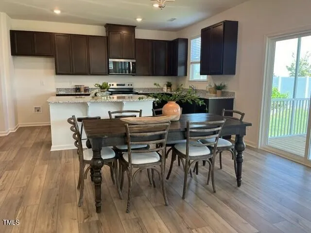 a kitchen with stainless steel appliances granite countertop a stove top oven a refrigerator a sink and a dining table with wooden floor