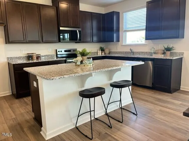 a kitchen with stainless steel appliances granite countertop a table chairs sink and cabinets