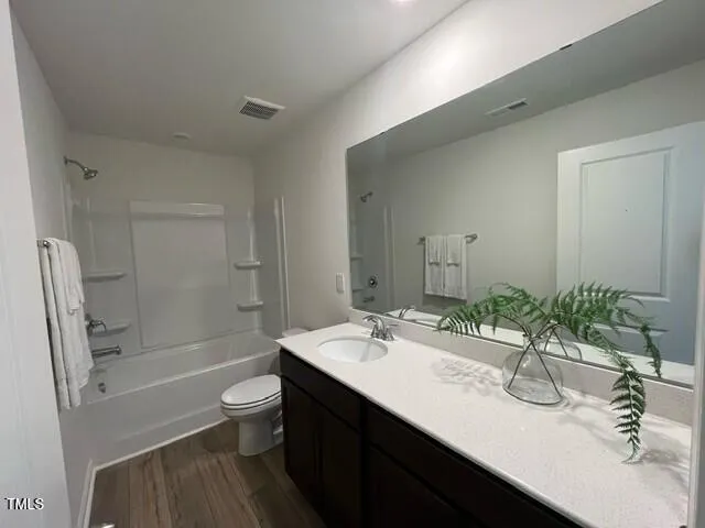 a bathroom with a granite countertop sink a toilet a mirror a bathtub and shower