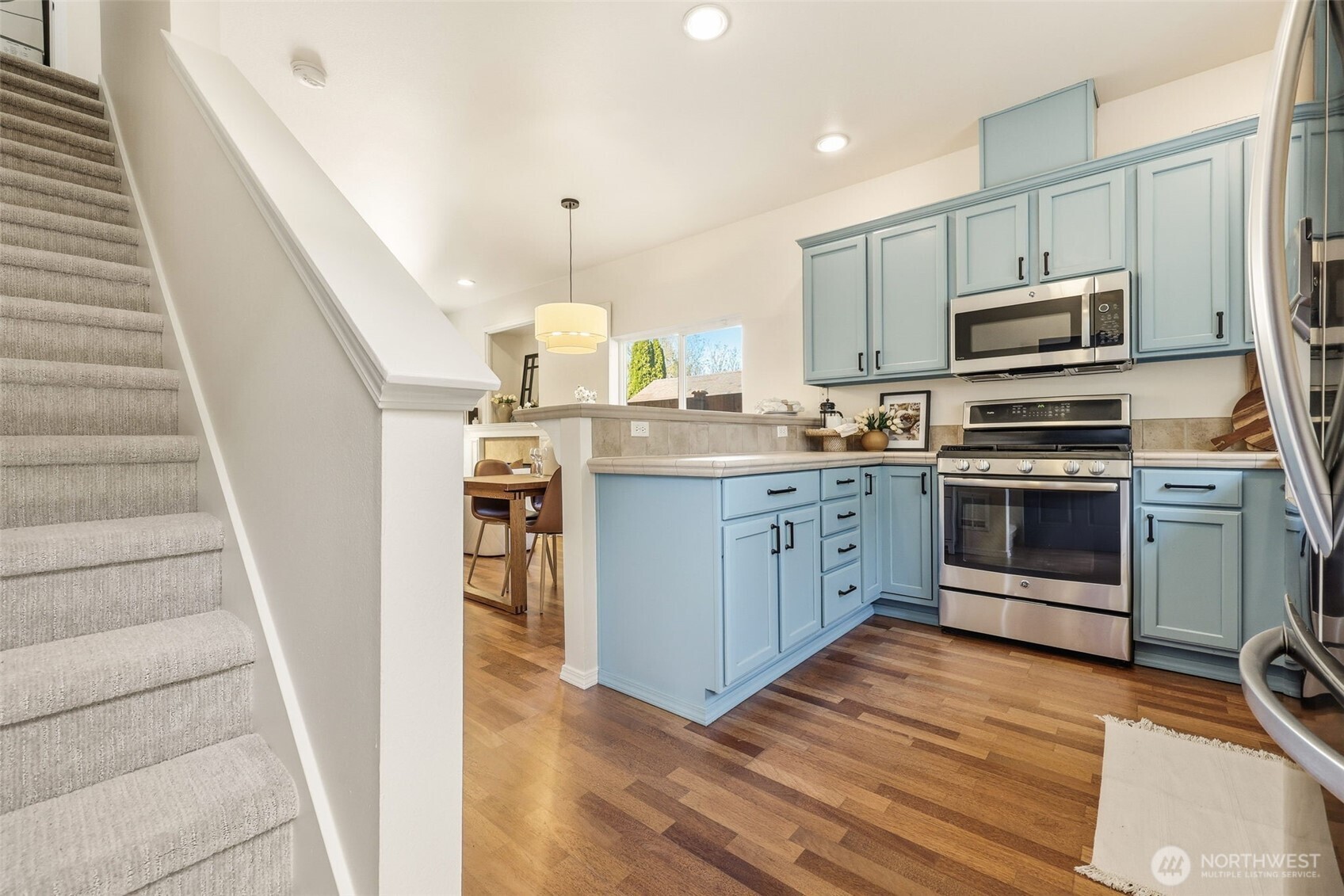 8847 9th Avenue Southwest, Unit A Seattle, WA 98106 - Photo 6 of 31 a kitchen with stainless steel appliances granite countertop a stove top oven a sink dishwasher and a refrigerator with wooden floor