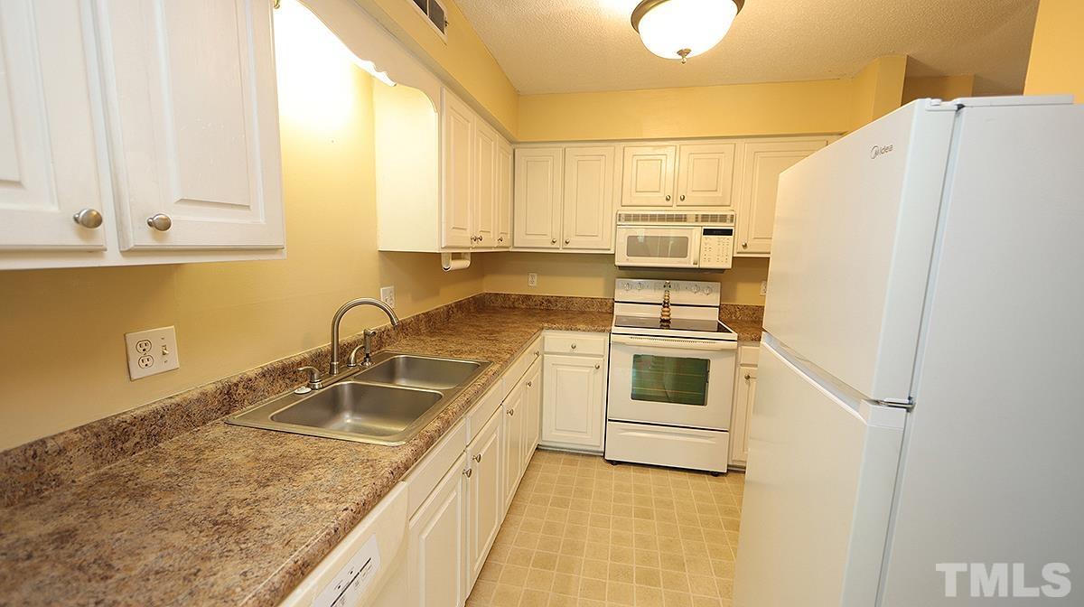 612 Pine Ridge Place, Unit 612 Raleigh, NC 27609 - Photo 2 of 12 a kitchen with granite countertop a sink and a refrigerator