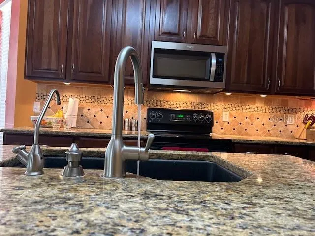a kitchen with granite countertop a stove and a microwave with wooden cabinets