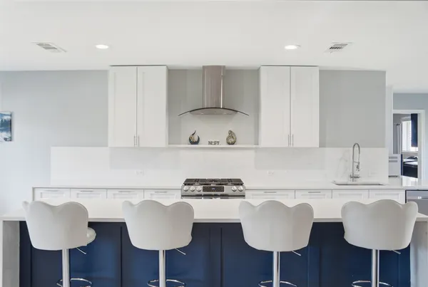 a kitchen with stainless steel appliances granite countertop a sink and a stove with white chairs