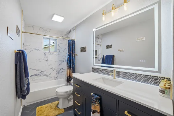 a bathroom with a granite countertop sink a toilet a mirror and shower
