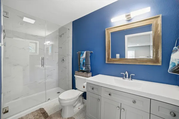 a bathroom with a toilet sink vanity and shower