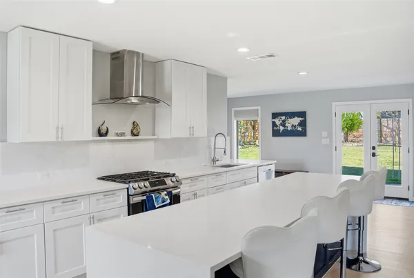 a kitchen with stainless steel appliances a sink a stove a refrigerator cabinets and a dining table