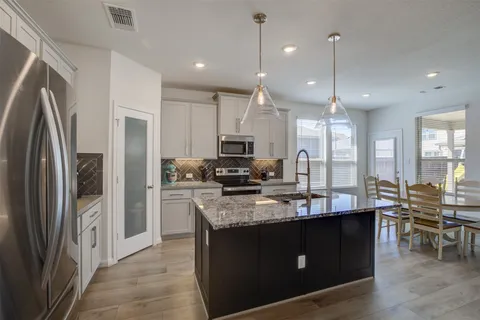 a large kitchen with stainless steel appliances kitchen island granite countertop a refrigerator a stove a sink and a microwave