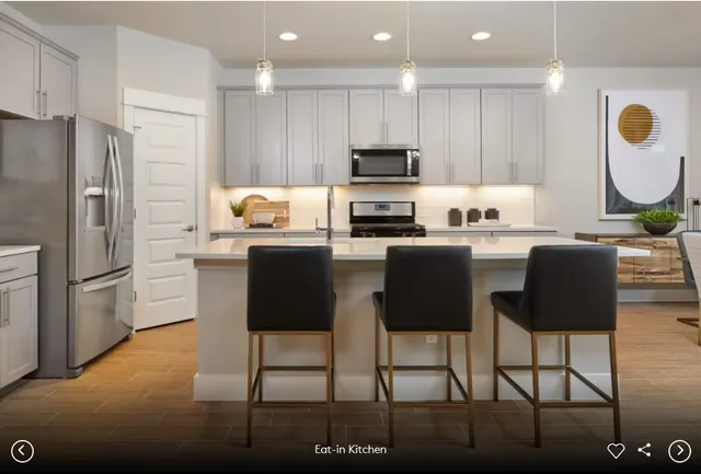 a kitchen with stainless steel appliances granite countertop a stove top oven a refrigerator a sink dishwasher a dining table and chairs with wooden floor