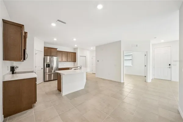 a large kitchen with stainless steel appliances a sink a stove a refrigerator a center island and couches