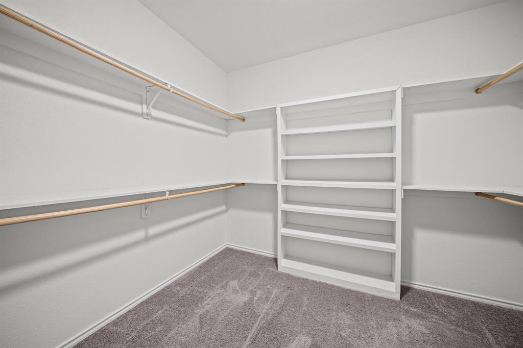 229 Firefly Drive Springtown, TX 76082 - Photo 14 of 33 Walk-in closet featuring built-in shelving, multiple hanging rods, and neutral-toned carpeting