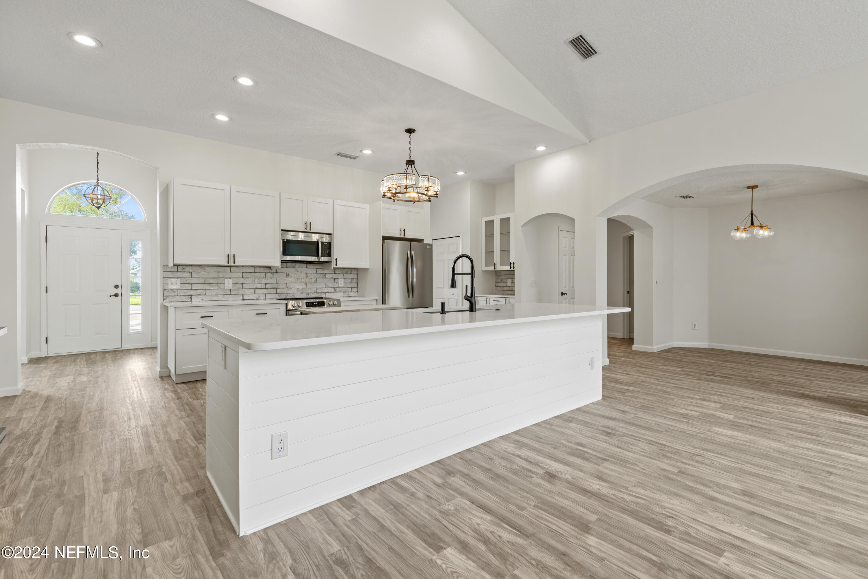156 Bilbao Drive St. Augustine, FL 32086 - Photo 16 of 57 a large white kitchen with kitchen island a sink dishwasher and a stove with wooden floor
