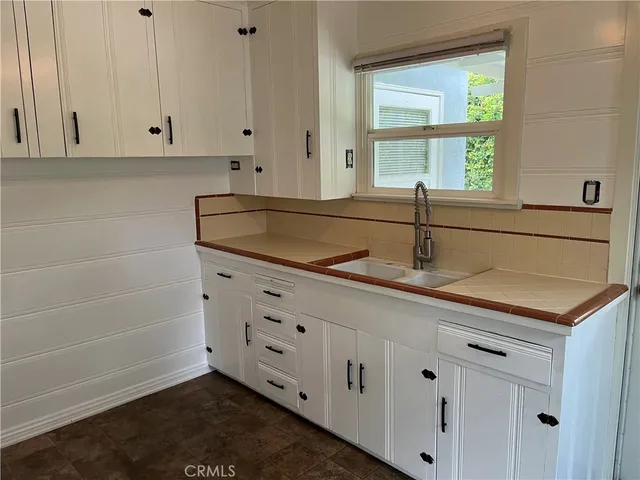 a kitchen with granite countertop white cabinets and a sink