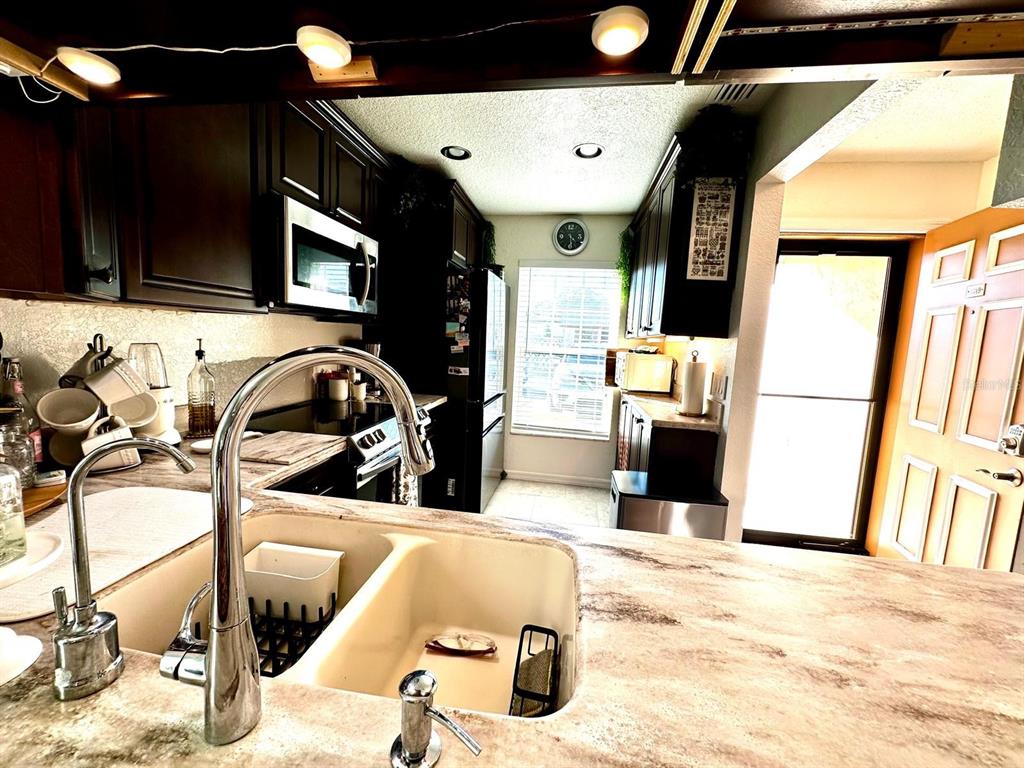 4749 Sunny Loop, Unit 4749 Holiday, FL 34690 - Photo 9 of 34 a kitchen with stainless steel appliances kitchen island granite countertop a sink and a microwave