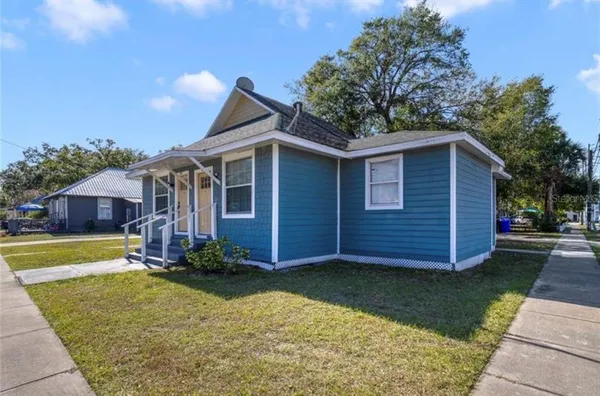 a view of a yard in front of a house with plants and large tree