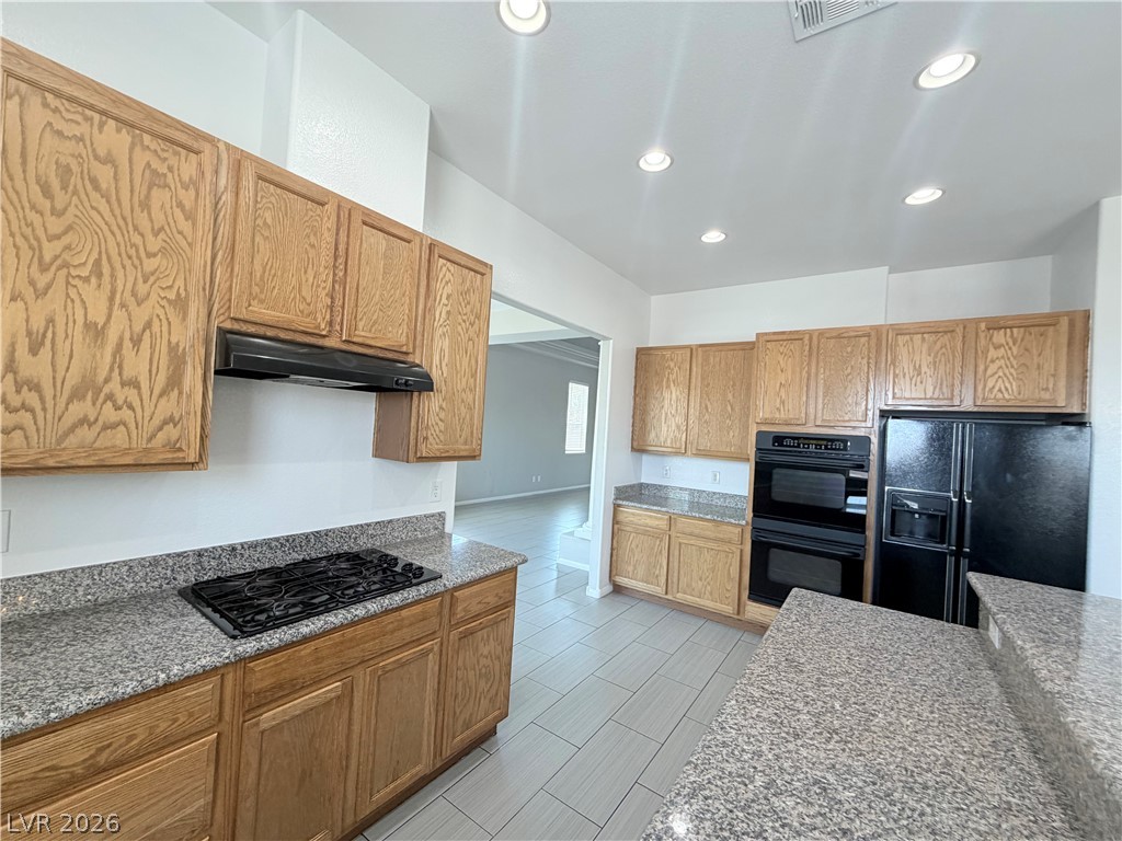 6116 Rabbit Track Street Las Vegas, NV 89130 - Photo 6 of 28 A well-equipped kitchen features granite counters, modern appliances, and warm wood cabinetry, ideal for culinary endeavors.