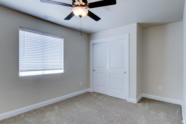 668 East Fiddlers Canyon Road, Unit 24 Cedar City, UT 84721 - Photo 13 of 21 Unfurnished bedroom with light colored carpet, a closet, and ceiling fan