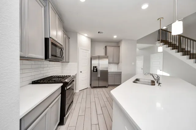 a kitchen with a sink a counter top space stainless steel appliances and cabinets