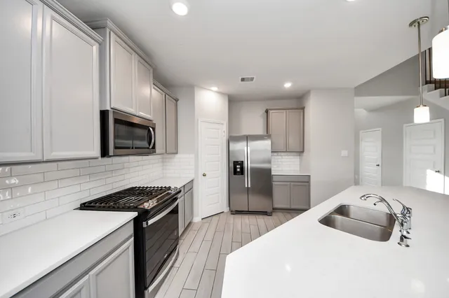 a kitchen with stainless steel appliances granite countertop a sink stove and refrigerator