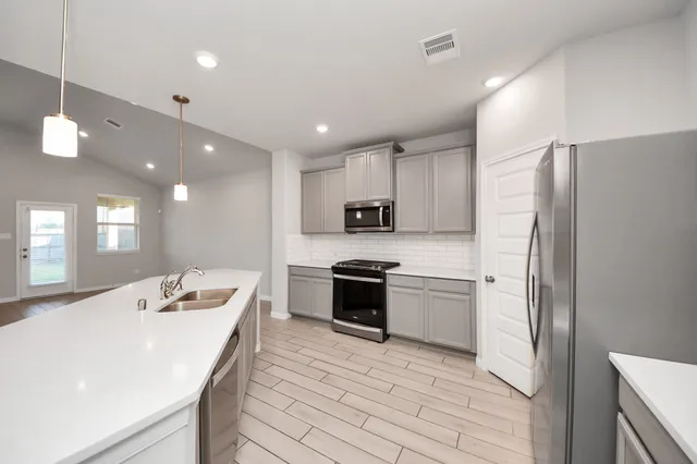 a kitchen with a refrigerator a stove top oven a sink dishwasher with wooden floor and cabinets