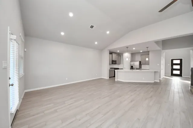 a view of large open kitchen with white cabinets and wooden floor