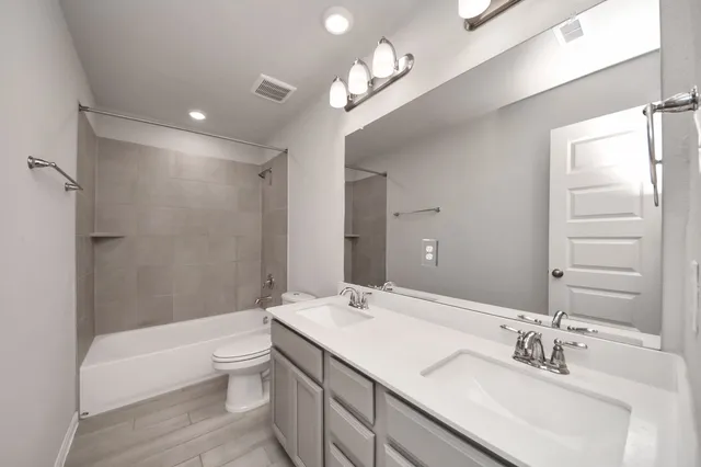a bathroom with a bathtub shower sink mirror and toilet