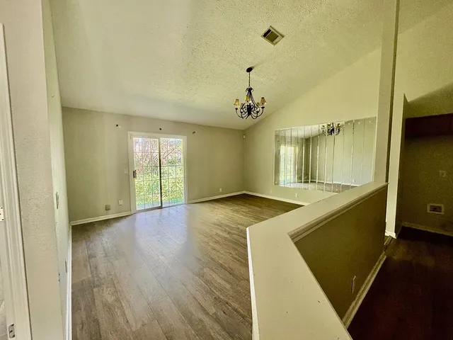 a view of an empty room with window and wooden floor